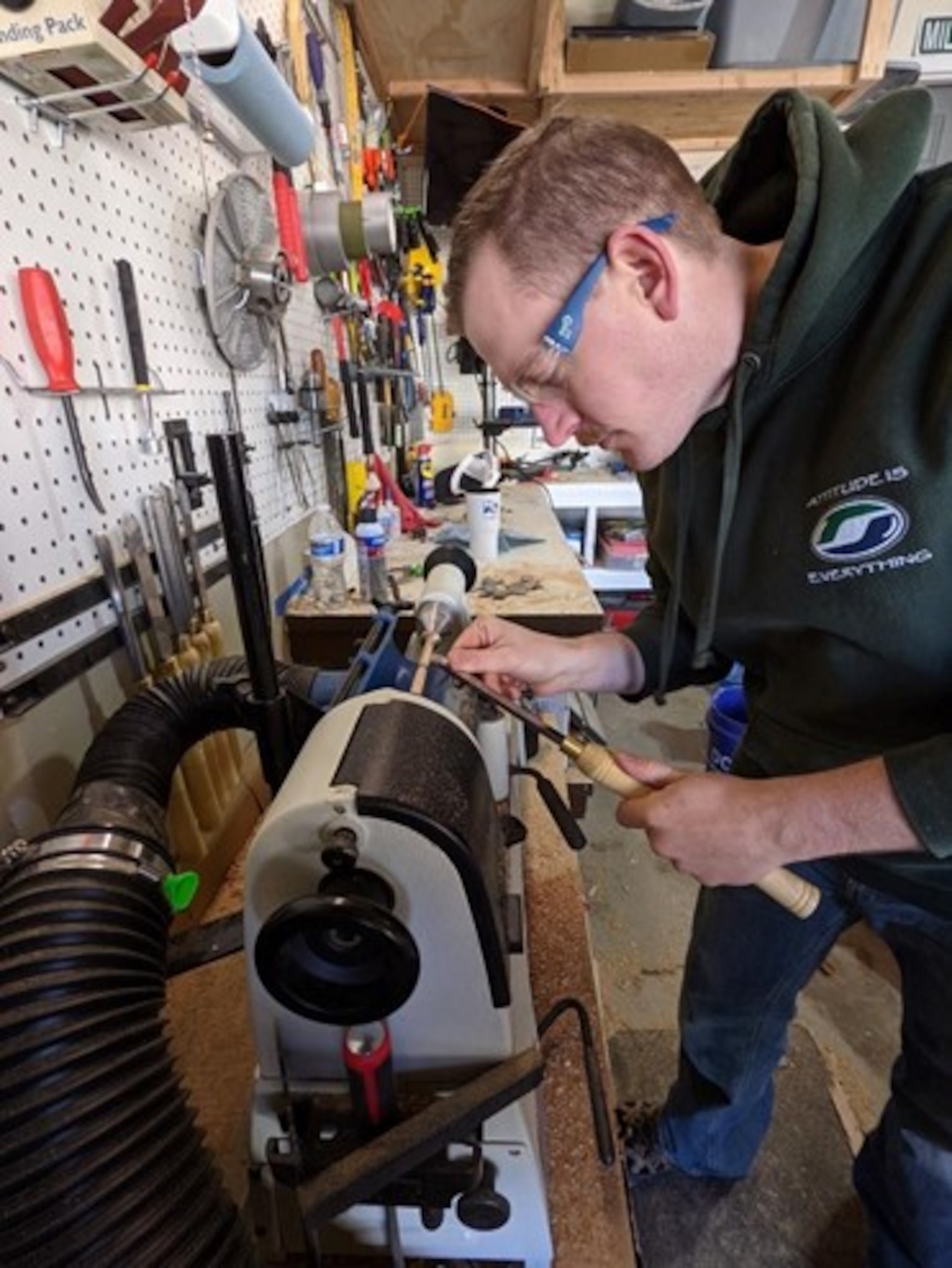 Picture of Capt. Ronald J. Miller bent over a lathe while holding a wooden pen.