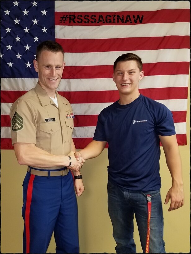 U.S. Marine Staff Sgt. Jonathon Sweet, the staff noncommissioned officer in charge of Recruiting Substation Northern Michigan, congratulates a newly enlisted Marine Corps poolee on his enlistment, Nov. 11, 2018.