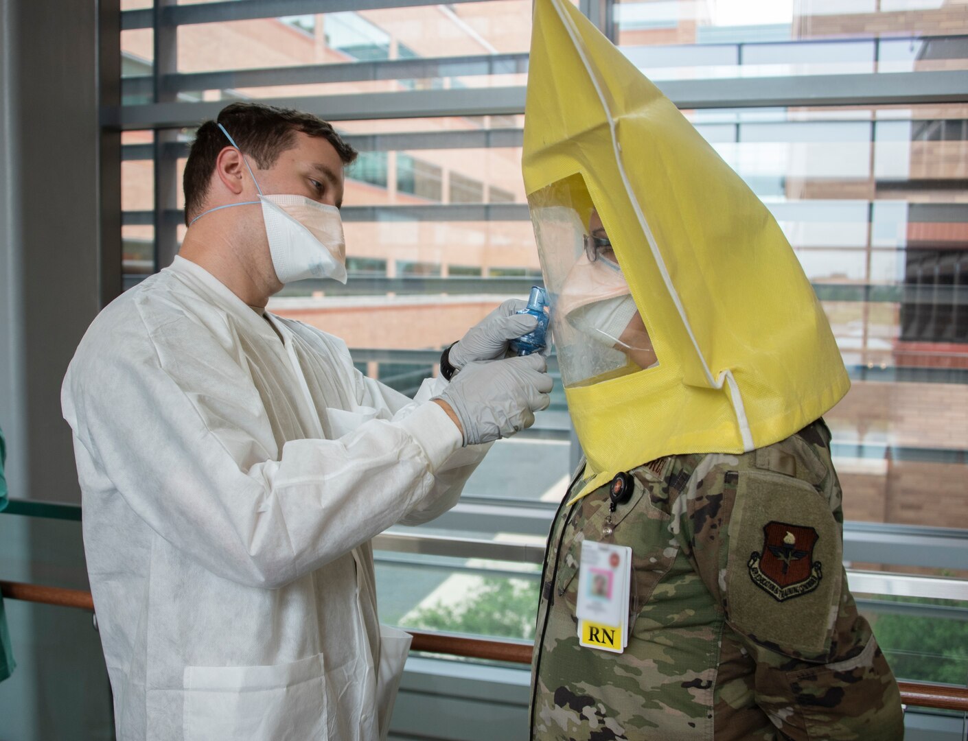 A soldier conducts a respirator fit test for an airman.