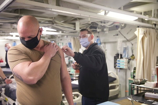 Command Master Chief Todd Mangin, command master chief for Expeditionary Strike Group (ESG 2), receives the COVID-19 vaccination aboard the amphibious transport dock ship USS San Antonio (LPD 17), Jan. 11, 2021.