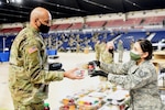 Tech. Sgt. Jennifer Zamudio, a member of the District of Columbia Air National Guard, distributes a meal to a Soldier at the D.C. National Guard Armory, Washington, D.C., Jan. 10, 2021. National Guard officials are stressing that the Soldiers and Airmen from all 50 states, three territories and Washington are receiving adequate food and lodging as they continue to support federal and local authorities leading up to the 59th presidential inauguration.