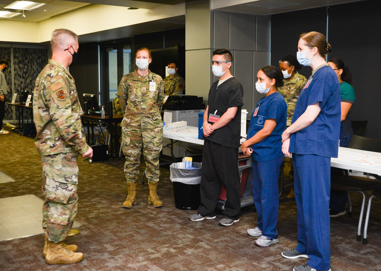 Lt. Gen. Timothy Haugh talks while standing in front of four medical center Airmen.
