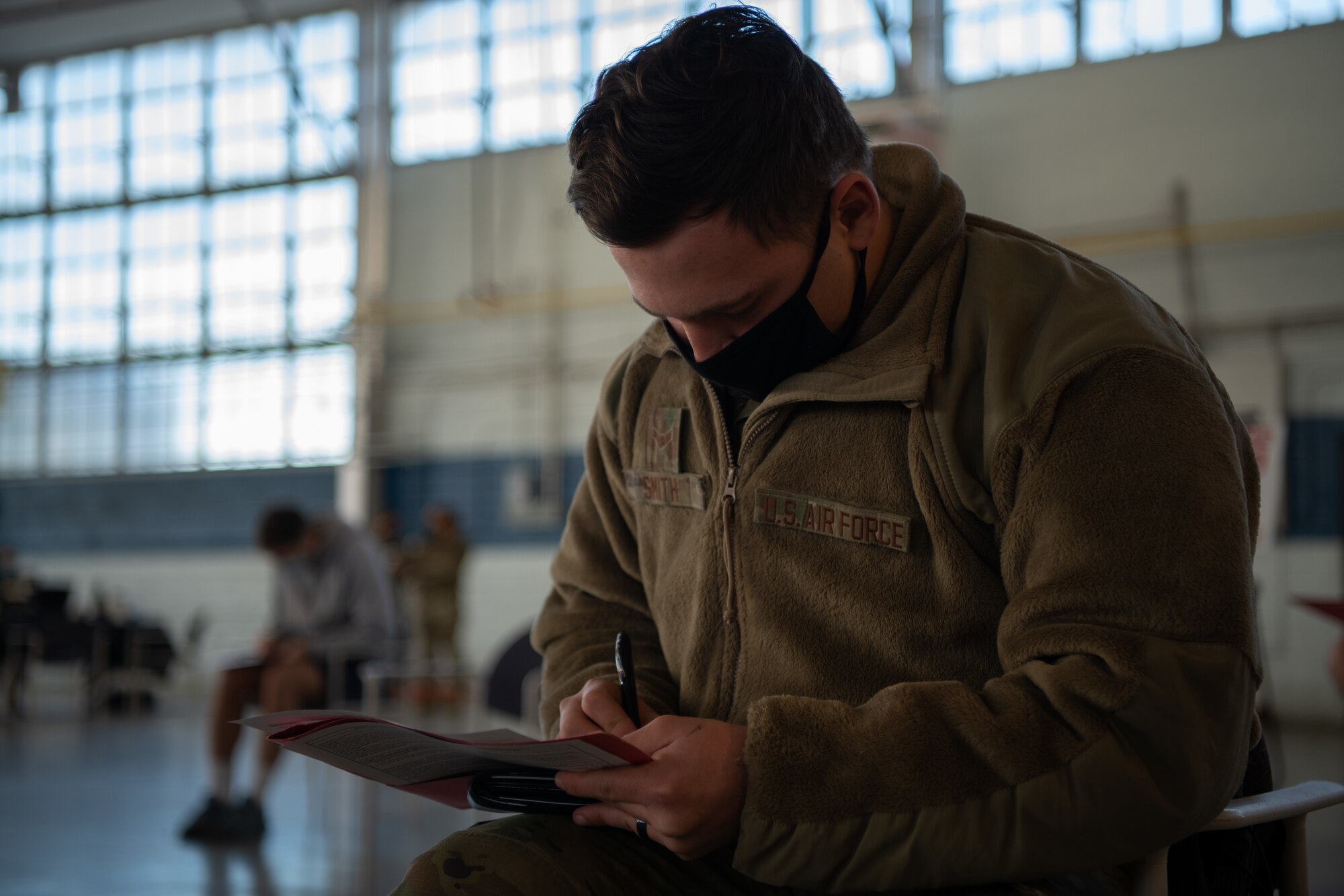 Airman 1st Class Dustin Smith, an Airman assigned to the 42nd Security Forces Squadron, fills out paperwork to check in Jan. 16, 2020, at the off-site clinic in the Honor Guard hangar on Maxwell Air Force Base, Alabama. Smith is one of the first Airmen on Maxwell to receive the vaccine, since emergency services personnel are prioritized in the population schema developed by the Department of Defense and Centers for Disease Control and Prevention.