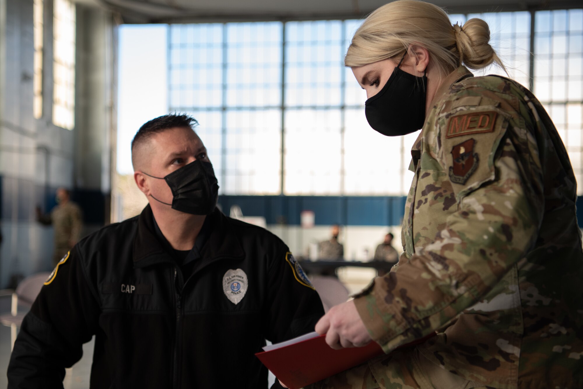 Capt. Aphton Lane, 42nd Medical Group Operation Warp Speed team lead, explains the “v-safe” program to Sgt. Richard Cap, a civilian defender and flight sergeant with the 42nd Security Forces Squadron, Jan. 16, 2020, at the off-site clinic in the Honor Guard hangar on Maxwell Air Force Base, Alabama. Recipients of the COVID-19 vaccine are encouraged to use the v-safe program to report any side effects and daily health to keep the vaccine process safe.