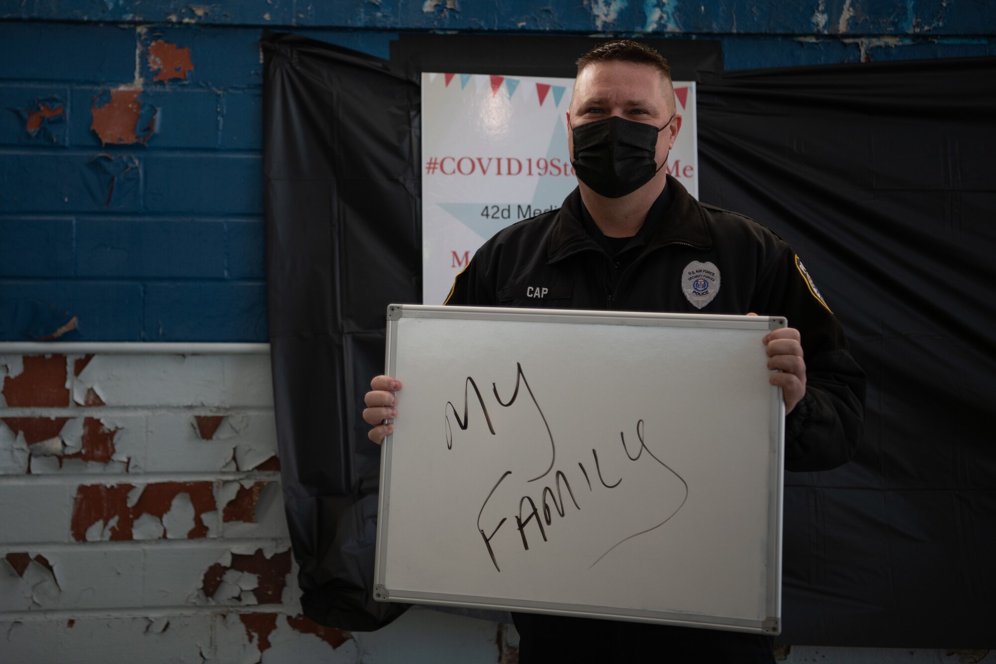 Sgt. Richard Cap, a civilian defender and flight sergeant with the 42nd Security Forces Squadron, holds up a sign with his reason for getting the COVID-19 vaccine Jan. 16, 2020, at the off-site clinic in the Honor Guard hangar on Maxwell Air Force Base, Alabama. After receiving the vaccine, patients can take a photo at the “I got the vaccine” selfie area.