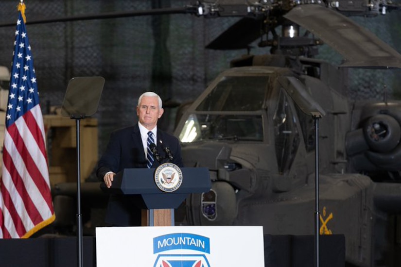 Man speaks to a hangar full of soldiers.