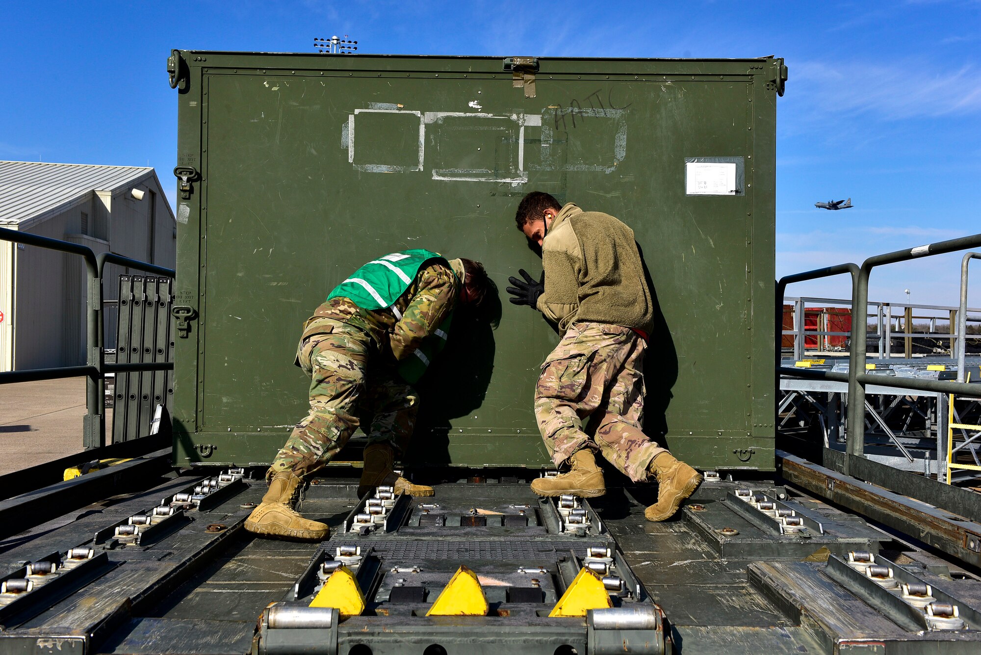 Two people push a container of equipment