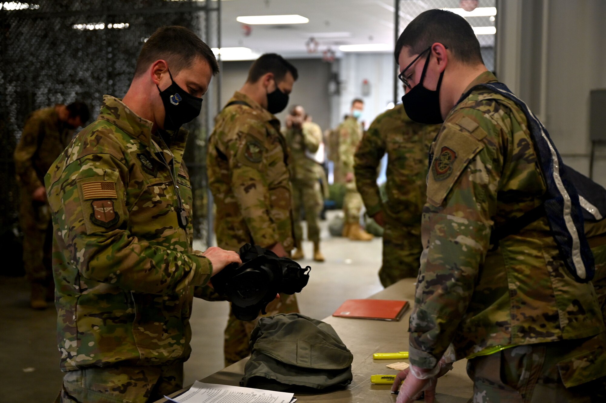A person inspects their gasmask upon checking it out from supply