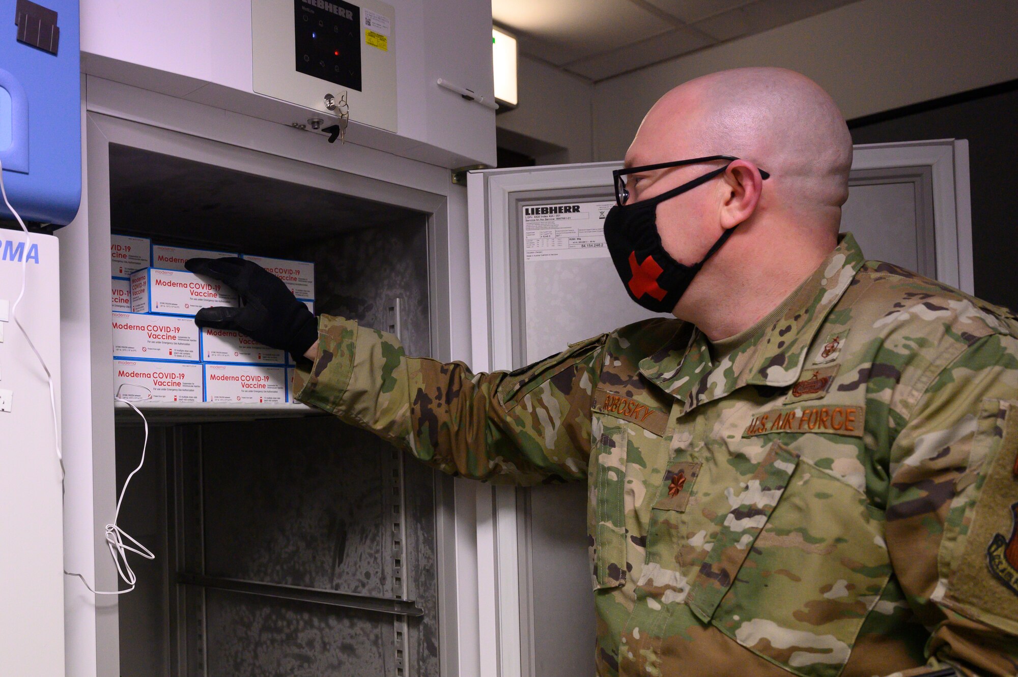 An Airman places COVID-19 vaccines into a freezer.
