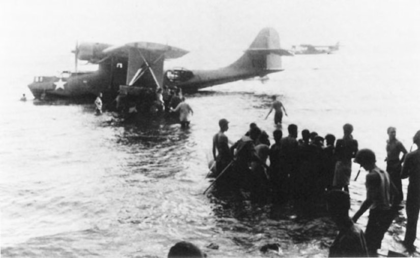 Troops wade to seaplane as it sits on the water.