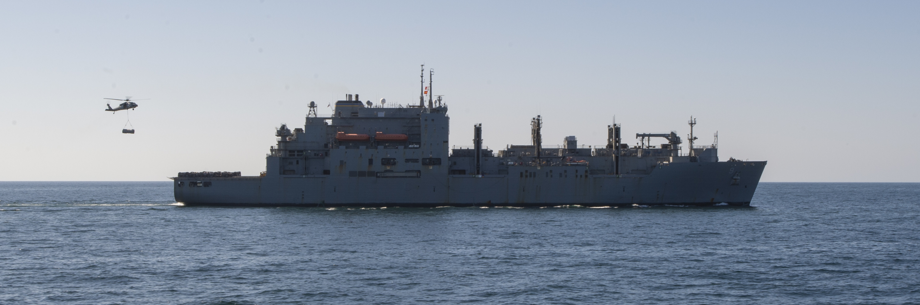 An MH-60S Sea Hawk helicopter, from the "Screamin' Indians" of Helicopter Sea Combat Squadron (HSC) 6, transports cargo from the flight deck of the Lewis and Clark-class dry cargo ship USNS Matthew Perry (T-AKE-9) during a replenishment-at-sea with the aircraft carrier USS Nimitz (CVN 68).