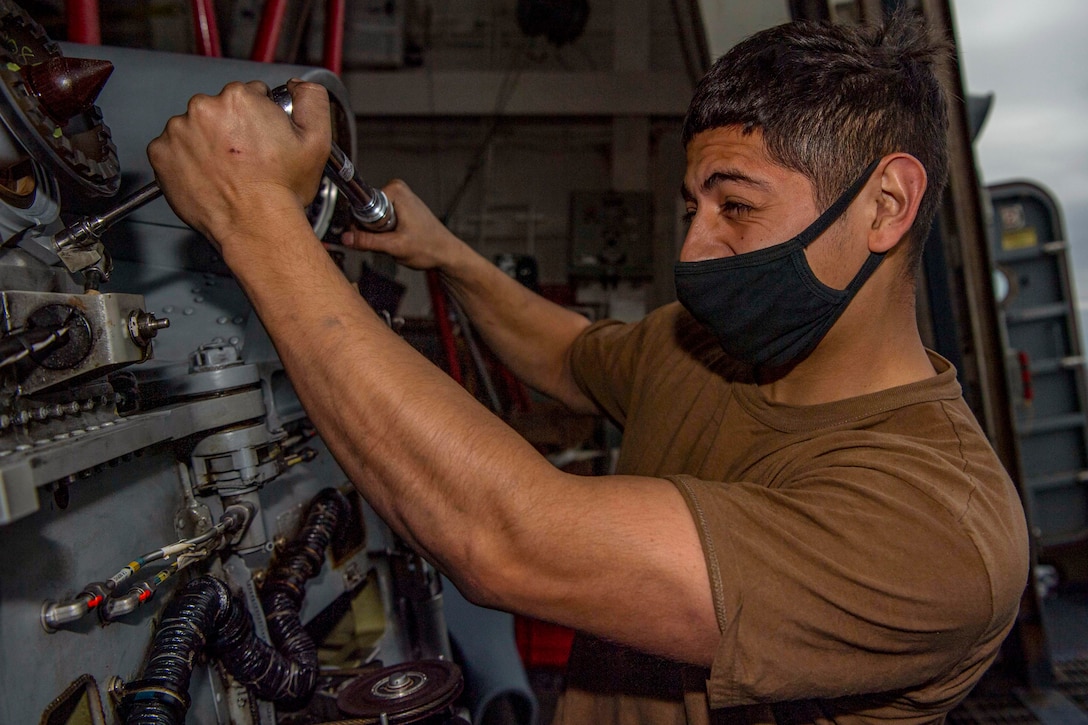 A sailor performs maintenance on a helicopter.