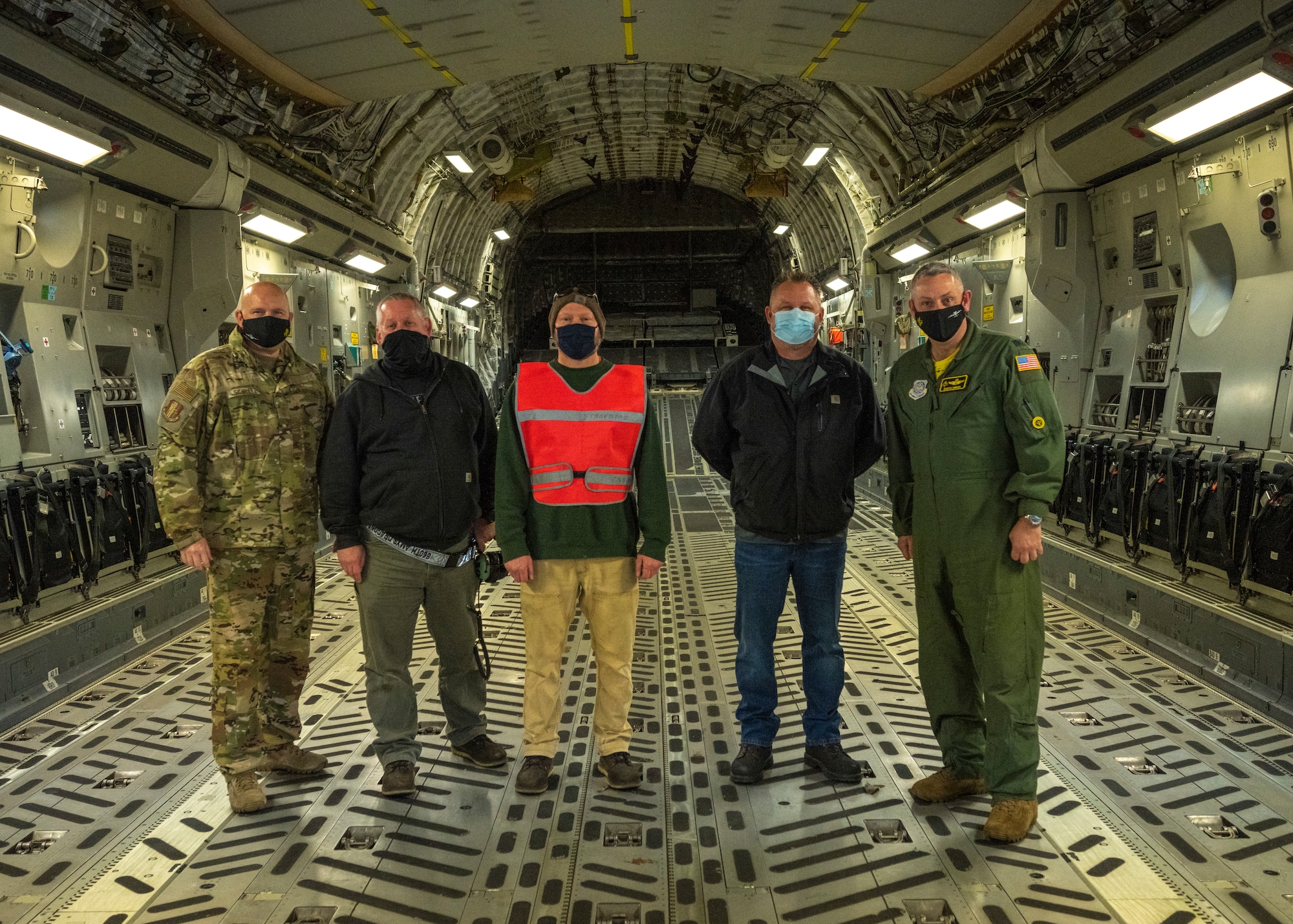 Individuals pose for a photo on a C-17 Globemaster III aircraft
