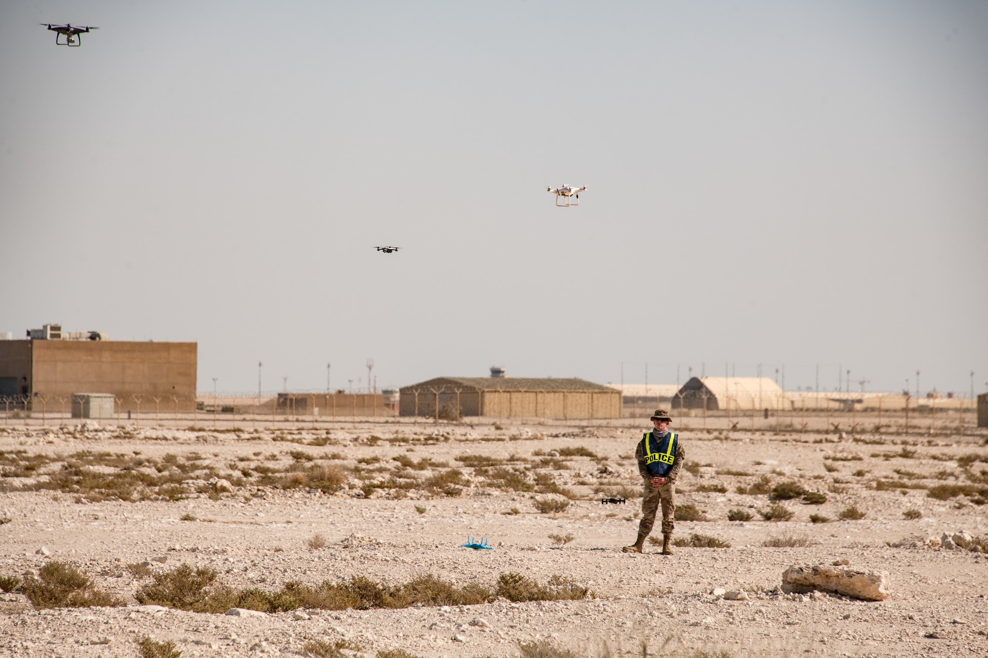 An Airman stands in a field surrounded by drones