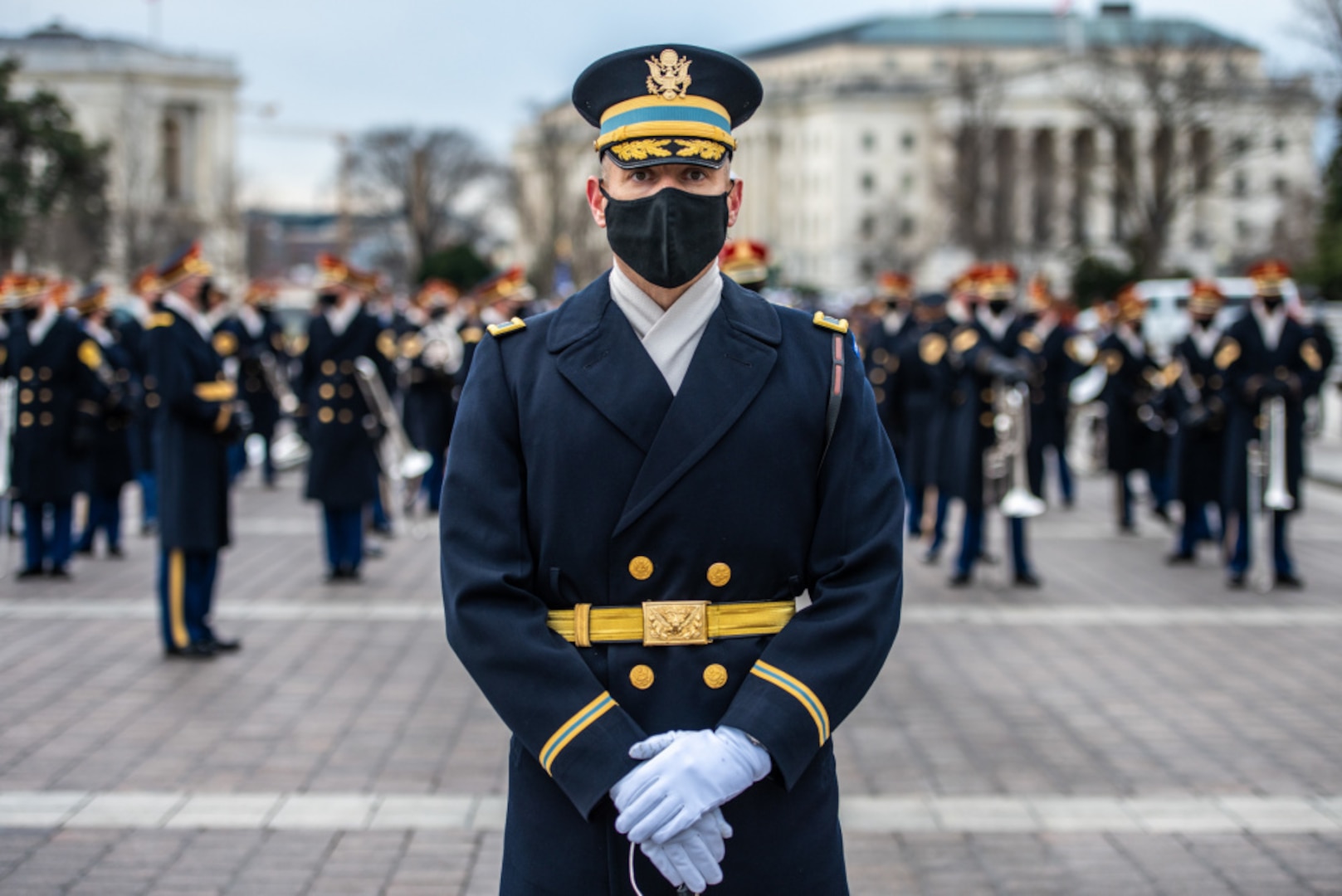 A soldier of the Army's Old Guard stands in the foreground of other soldiers all in service dress.