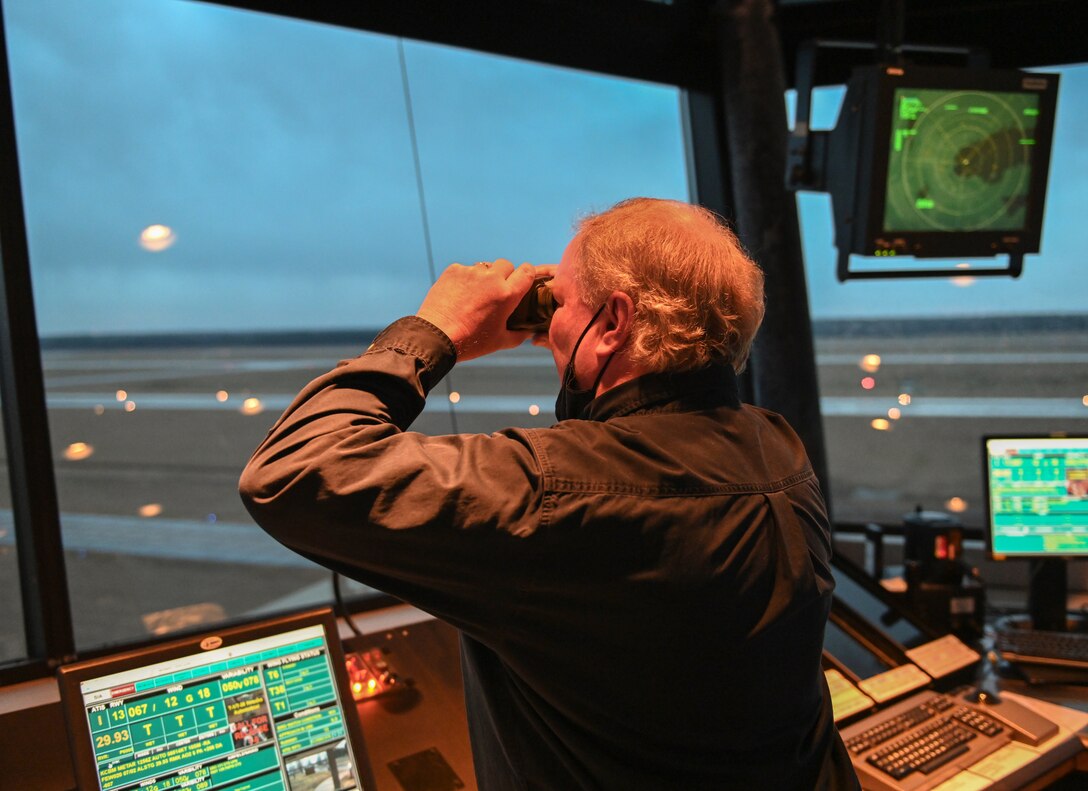 Retired U.S. Air Force Master Sgt. Walter Boltwood, Radar Approach Control (RAPCON) chief controller, looks through binoculars as a T-6A Texan II prepares to taxi on a runway on Jan. 7, 2020, at Columbus Air Force Base, Miss. The pilot in the T-6 was Lt. Col. Jennifer Prouty, 14th Operations Support Squadron commander. Prouty wanted Boltwood to clear her for take-off to acknowledge the anniversary. (U.S. Air Force photo by Airman 1st Class Davis Donaldson)