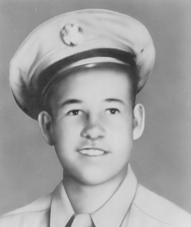 An old photograph shows a young man dressed in a military uniform smiling at the camera.