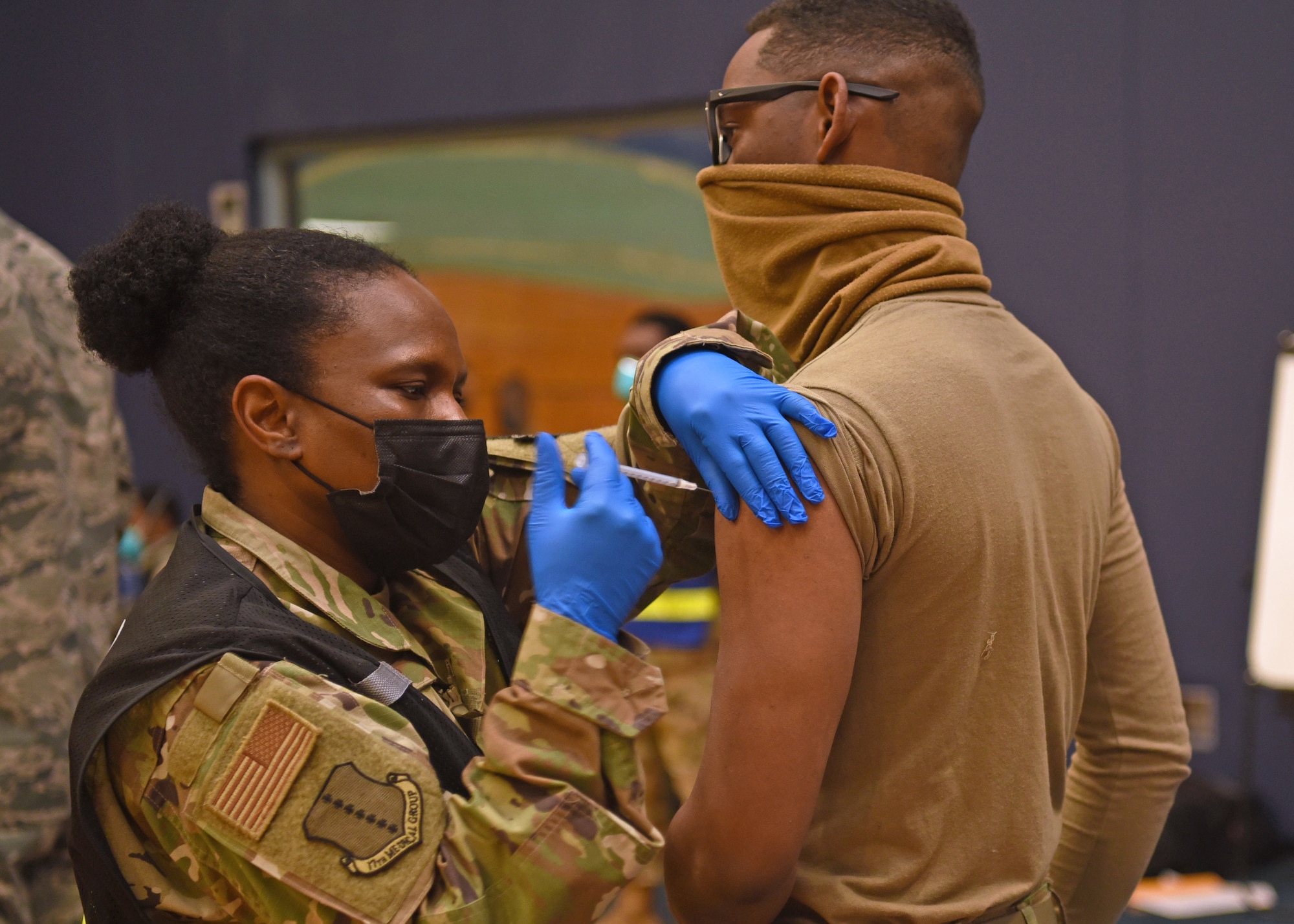 U.S. Air Force Lt. Col. Cynthia Ennis, 17th Medical Group command staff healthcare integrator, administers the first COVID-19 vaccine to Airman 1st Class Earl Newton, 17th Security Forces Squadron entry controller, at the immunization clinic inside the Mathis Fitness Center on Goodfellow Air Force Base, Texas, Jan. 20, 2021. Newton volunteered for the first round of COVID-19 vaccinations, which were distributed to Goodfellow personnel based on a predetermined priority. (U.S. Air Force photo by Senior Airman Abbey Rieves)