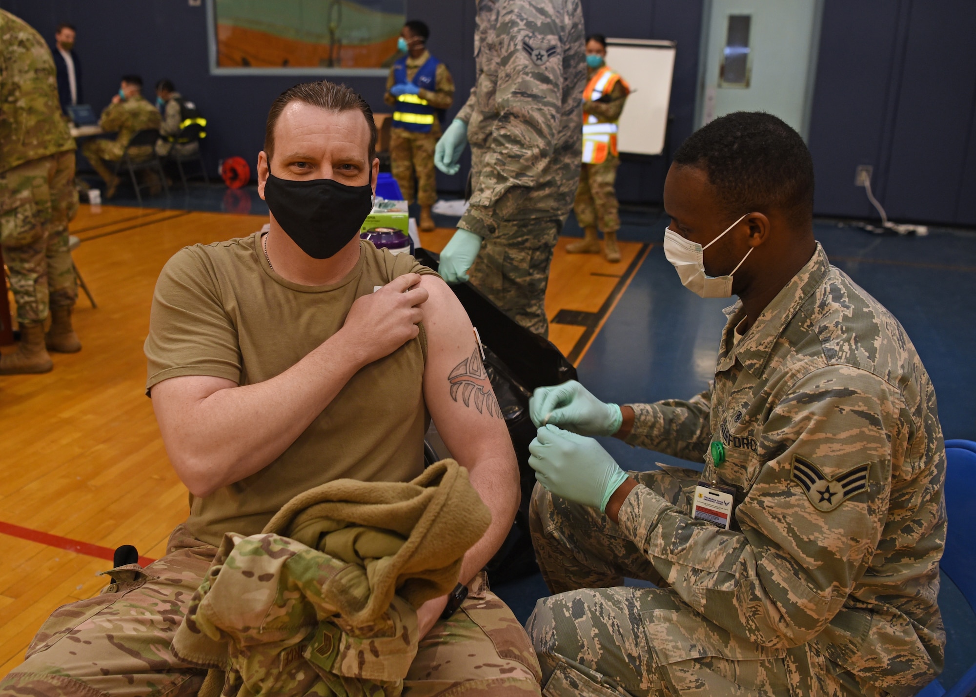 U.S. Air Force Tech Sgt. Aaron January, 17th Security Force Squadron flight sergeant, rolls up his sleeve for Senior Airman Marckus Humphries, 17th Operational Medical Readiness Squadron aerospace medical technician, to prepare his shoulder for the COVID-19 vaccine at the Mathis Fitness Center on Goodfellow Air Force Base, Texas, Jan. 20, 2021. Team Goodfellow vaccinated its frontline and mission essential positions, and those who are considered high risk first, in accordance with the Department of the Air Force’s distribution plan. (U.S. Air Force photo by Senior Airman Abbey Rieves)