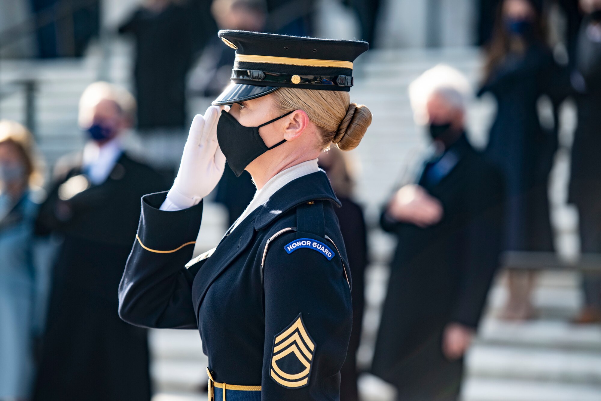A soldier salutes at an outdoor ceremony.