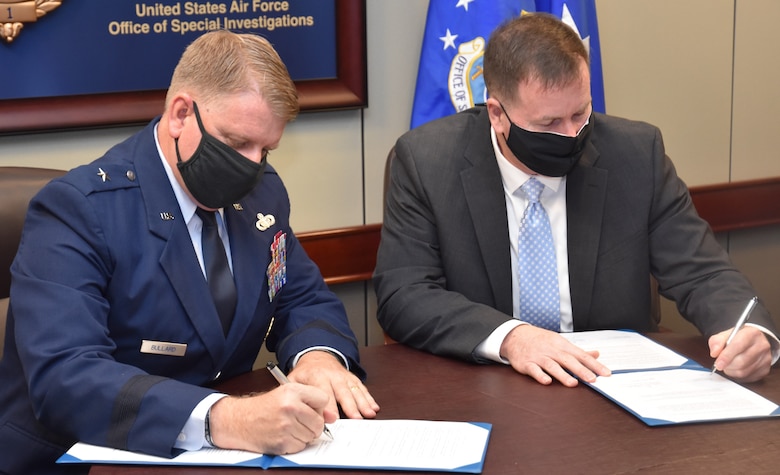 Brig. Gen. Terry L. Bullard, Office of Special Investigations commander, and Jeffrey D. Specht, Department of Defense Cyber Crime Center (DC3) executive director, sign documents during a ceremony Jan. 20, 2021, at OSI Headquarters in Quantico, Va. to observe the establishment of DC3 as a Field Operating Agency.