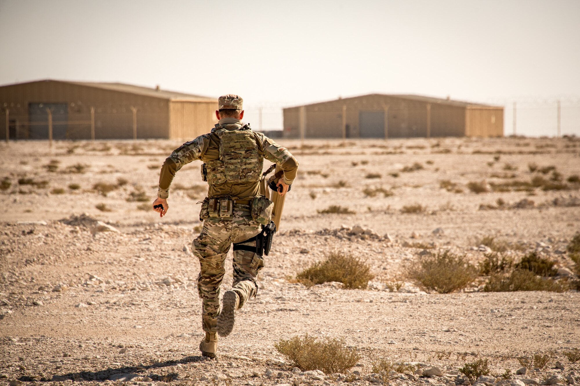 An airman runs with a signal interruption device toward drones