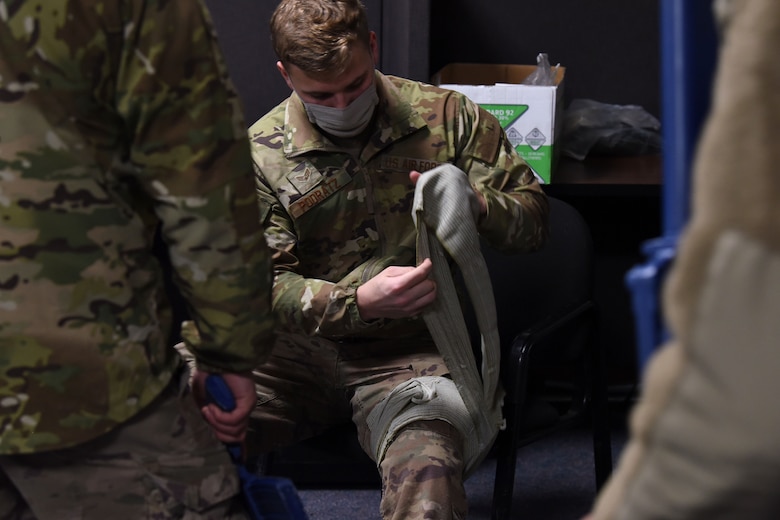 An Airmen wraps bandages around his leg to teach a group of Airmen practical medical procedures to use during a combat situation.