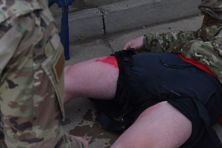 The lower half of an Airman's body with a tourniquet on both legs with a moderate amount of blood showing.