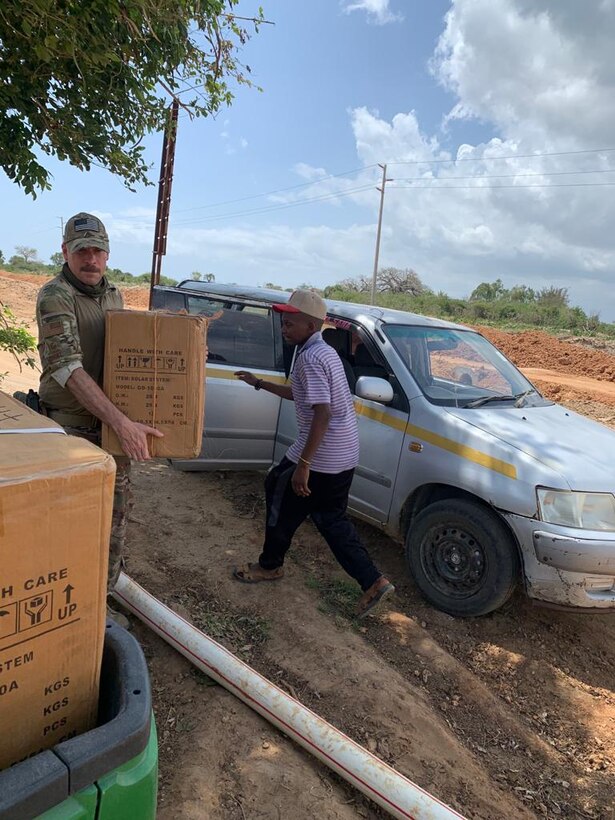 A U.S. service member and Kenyan volunteer carry supplies to the site of the primary school in Magogoni Village, Lamu, Kenya, Dec. 10, 2020.