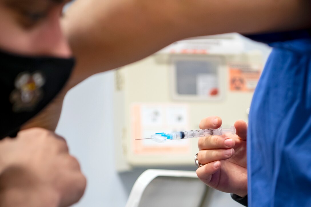 An Airman from the 423rd Medical Squadron, prepares to administer the COVID-19 vaccine to a Department of Defense Education Activity teachers at RAF Alconbury, England, Jan. 7, 2020. DoDEA teachers are receiving the vaccine in an effort to reduce the potential spread of COVID-19 within the schools and community. (U.S. Air Force photo by Senior Airman Eugene Oliver)