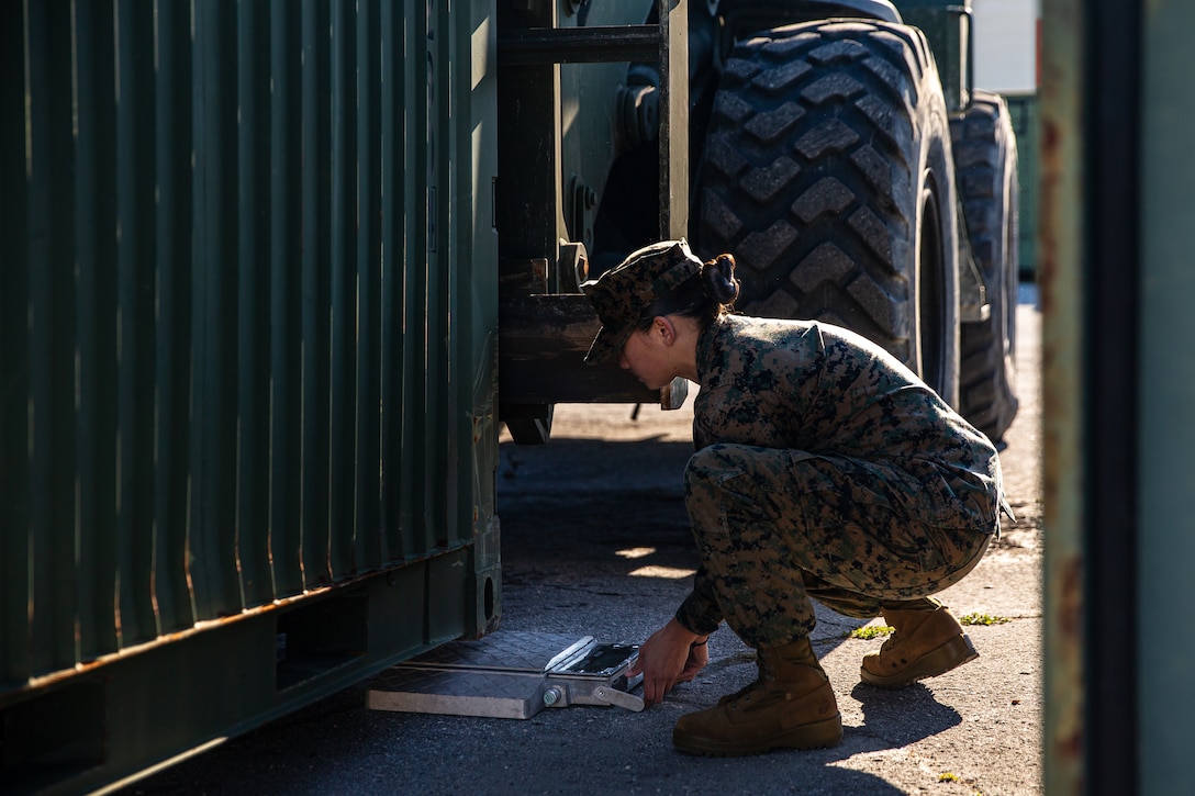 U.S. Marine Corps Sgt. Anthonette Bement, an embarkation specialist with the 26th Marine Expeditionary Unit, places a scale under a quadcon.