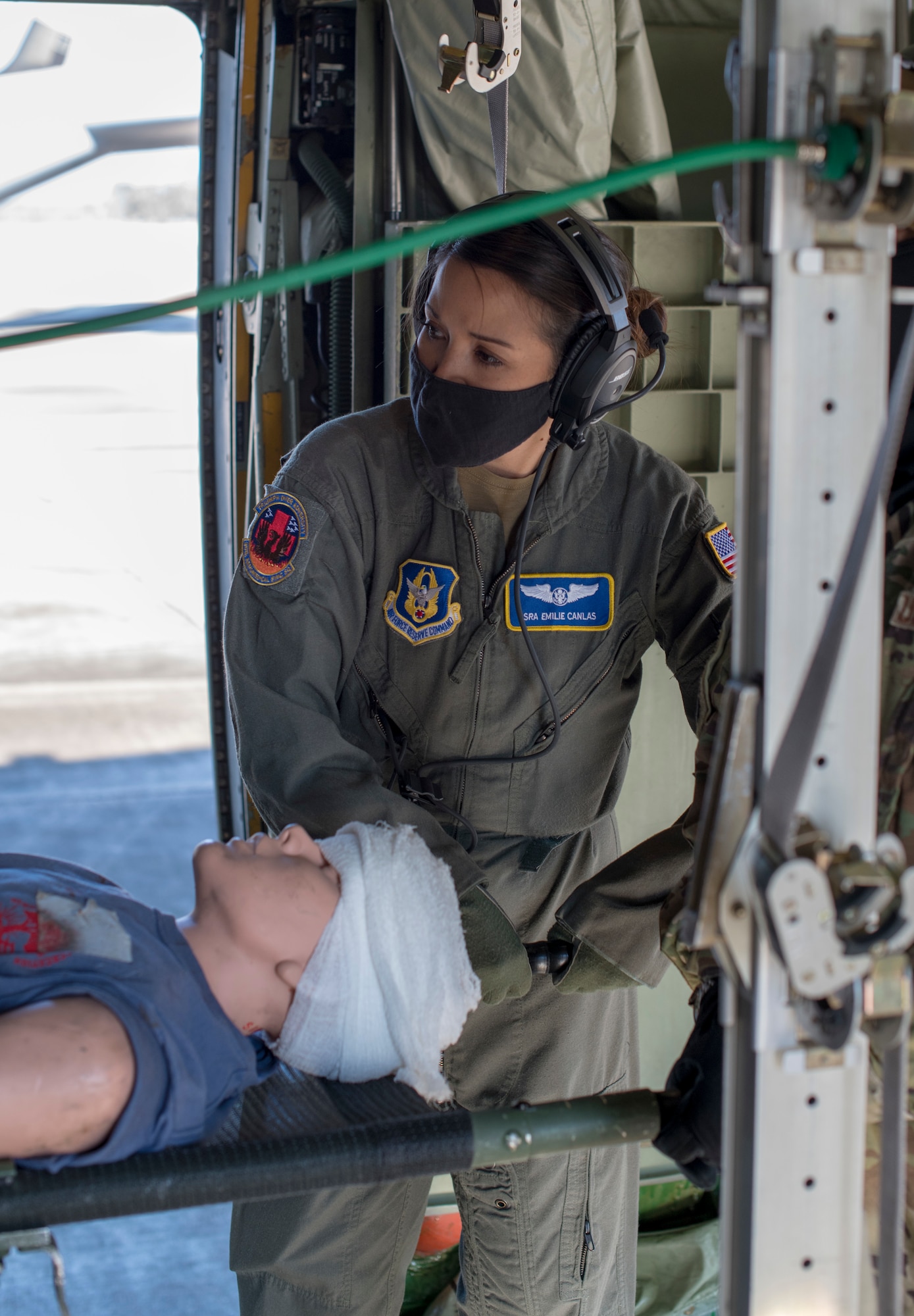 Senior Airman Emilie Canlas, flight medic for the 36th Aeromedical Evacuation Squadron, awaits the cue to raise the litter during a pre-deployment exercise at Keesler Air Force Base, Miss., Jan. 13, 2021. Canlas volunteered early during the COVID-19 pandemic to deploy and assist with the transport and care of COVID-19 patients.(U.S. Air Force photo by Senior Airman Kristen Pittman)