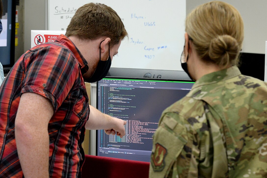 Brig. Gen. Vanessa Dornhoffer (right), mobilization assistant to commander for the Ogden Air Logistics Complex, receives a briefing on code from Morgan Jensen, a member of the 309th Software Engineering Group’s Software Organizational Development Office team. Jensen is pointing at a computer screen.
