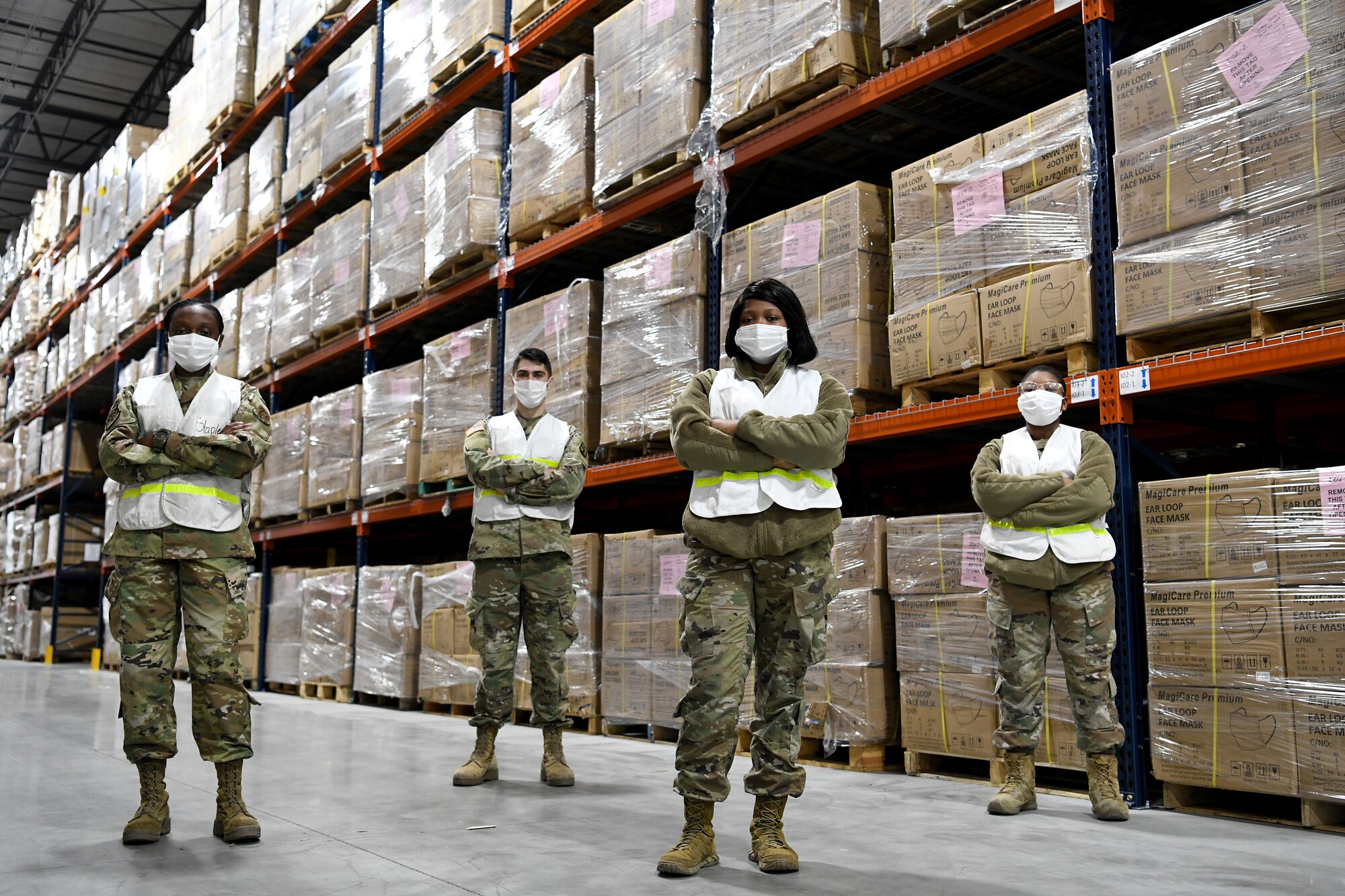 Four service members pose for a group portrait inside a medical supply warehouse.