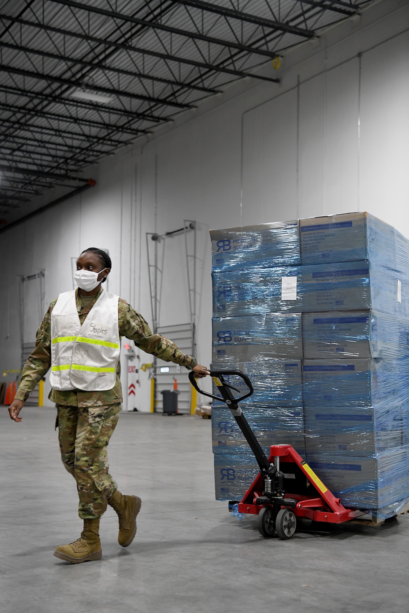 An Airman transports a pallet of medical supplies in a warehouse.