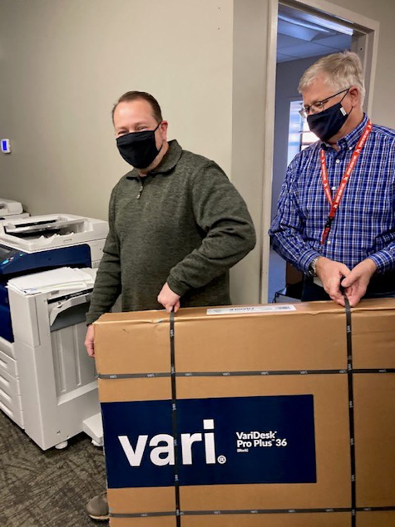 George Scheers helps Paul Jensen move the last pieces of furniture into offices.