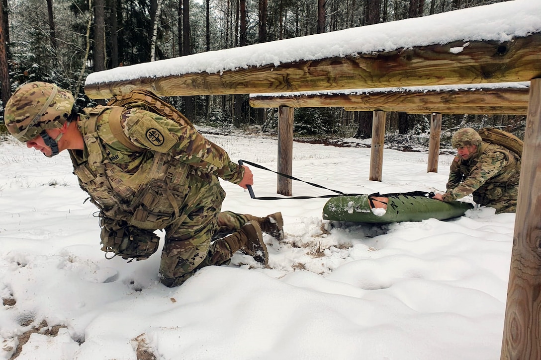 Soldiers evacuate a simulated injured soldier in the snow for training.