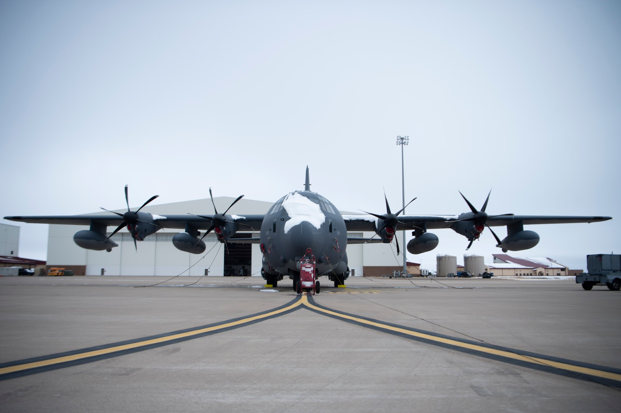 Snow sits on the nose of an aircraft (center screen) on the flightline