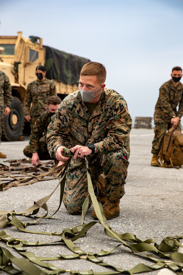 U.S. Marine Corps Cpl. Ashton Bailey, a landing support specialist with 3rd Landing Support Battalion, 3rd Marine Logistics Group, adjusts the nets for palletized gear during deployment preparation on Kadena Air Force Base, Okinawa, Japan, Jan. 21, 2021. 3rd MEB practices distributed operations as part of the Marine Corps’ only forward-deployed force. (U.S. Marine Corps photo by Lance Cpl. Natalie Greenwood)