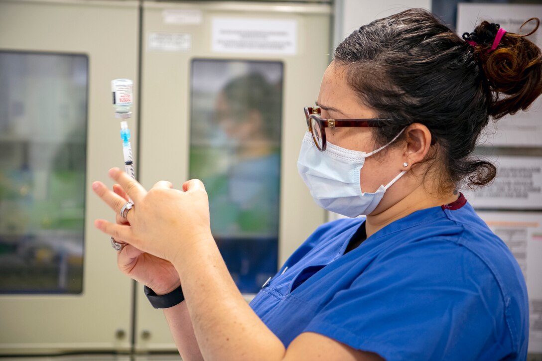 U.S. Air Force Tech. Sgt. Yarely Jerez-Ortiz, 423rd Medical Squadron family practice flight chief, prepares to administer the COVID-19 vaccine at RAF Alconbury, England, Jan. 7, 2020. Department of Defense Education Activity teachers are receiving the vaccine in an effort to reduce the potential spread of COVID-19 within the schools and community. (U.S. Air Force photo by Senior Airman Eugene Oliver)