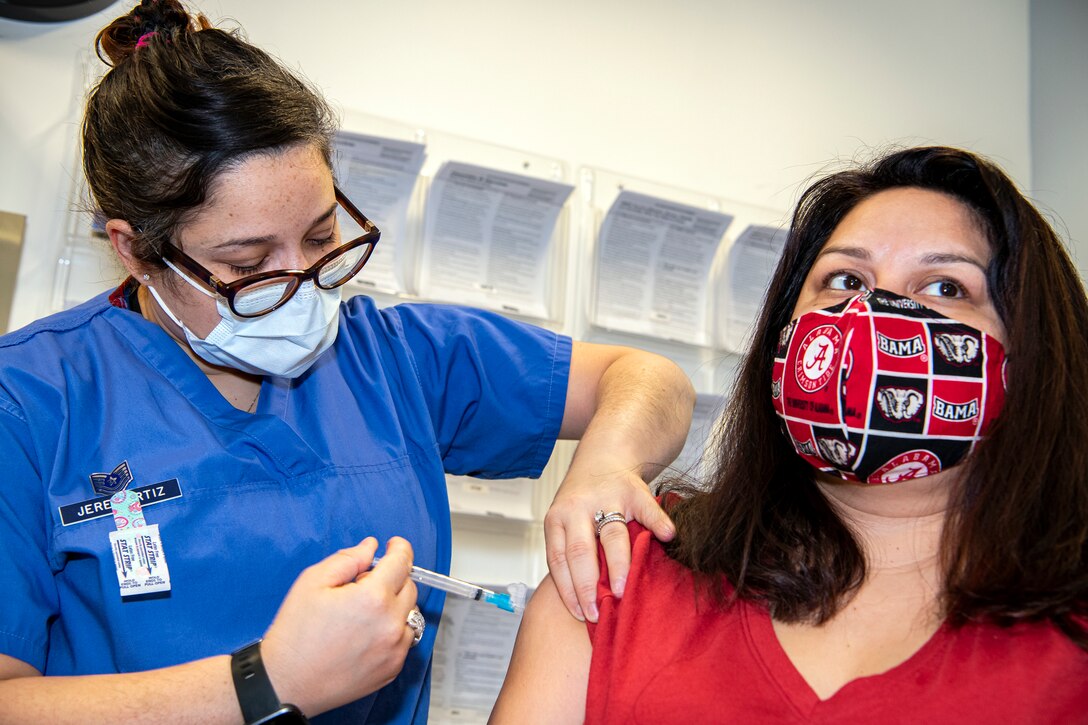 U.S. Air Force Tech. Sgt. Yarely Jerez-Ortiz, right, 423rd Medical Squadron family practice flight chief, administers the COVID-19 vaccine to a Department of Defense Education Activity teacher at RAF Alconbury, England, Jan. 7, 2020. DoDEA teachers are receiving the vaccine in an effort to reduce the potential spread of COVID-19 within the schools and community. (U.S. Air Force photo by Senior Airman Eugene Oliver)
