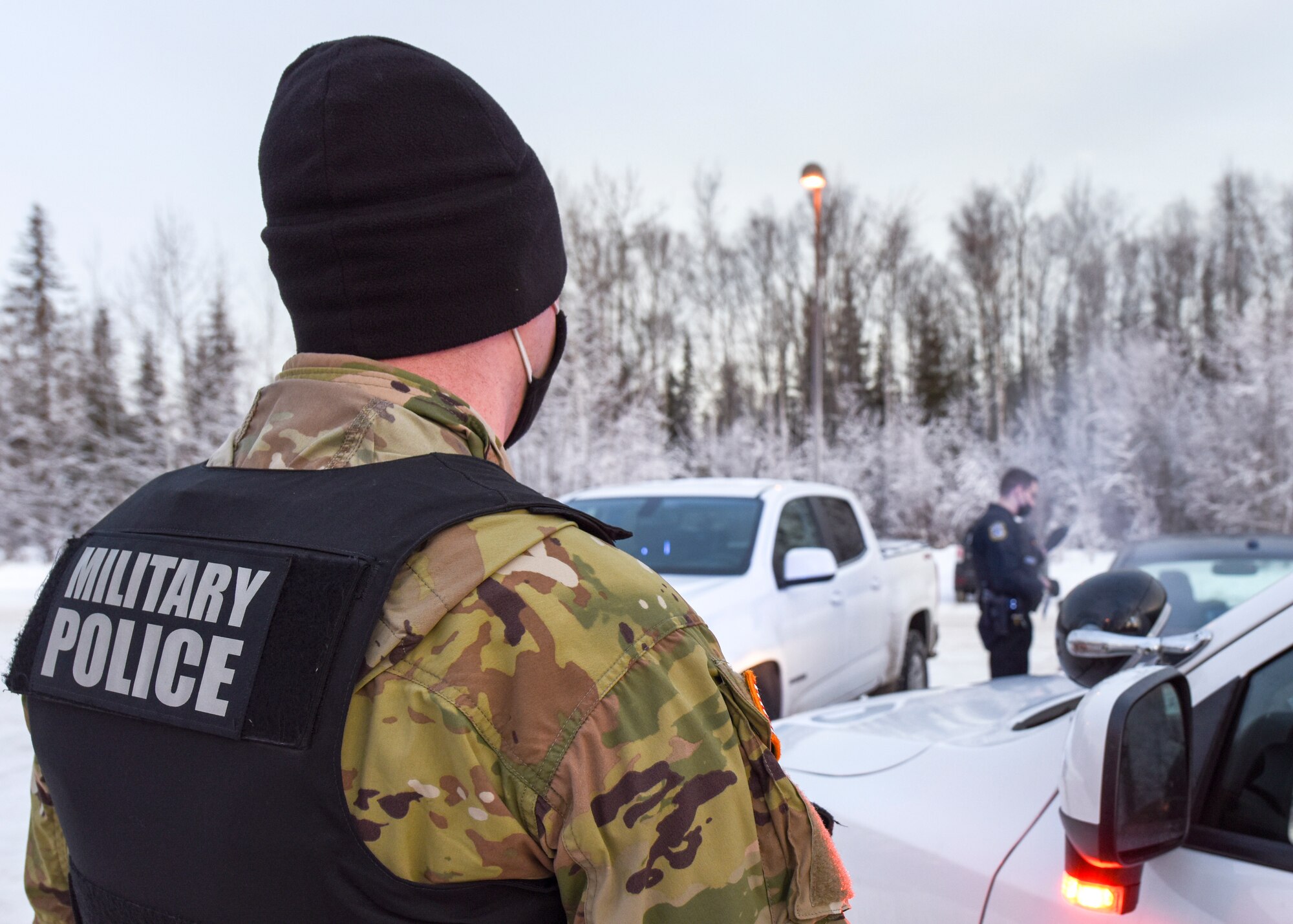 U.S. Army Sgt. Tyler Burns, assigned to the 545th Military Police Detachment/673d Security Forces Squadron patrolman stands watch for Department of Defense Police Officer Richard Martinez, a patrol officer with the 673d SFS, during a routine stop Jan. 8, 2021, at Joint Base Elmendorf-Richardson, Alaska. The 673d SFS has begun integrating 60 new, high-tech body cameras into daily operations after the adaptable technology reached a point of not only being a reliable safety and training instrument, but a multifunctional accountability tool serving all. (U.S. Air Force photo by Senior Airman Crystal A. Jenkins)