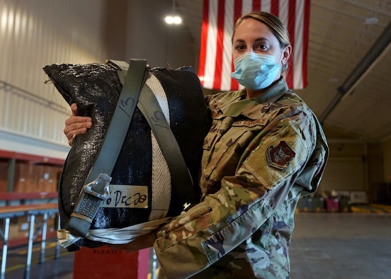 Staff Sgt. Makenzie Carlson, 919th Special Operations Logistic Readiness Squadron air transportation specialist, poses with a freshly packed parachute at Duke Field, Florida, Dec. 29, 2020.