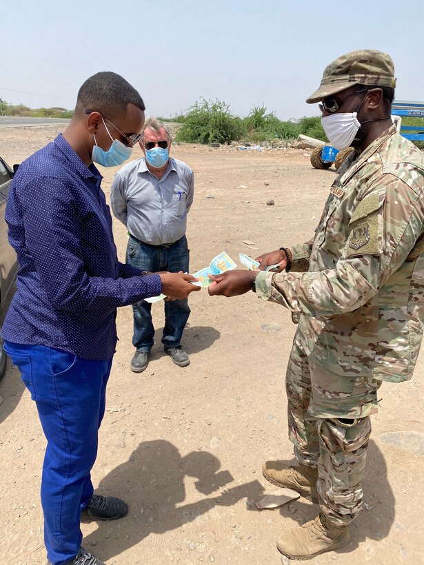 A photo of an Airman exchanging money with a Djiboutian national.