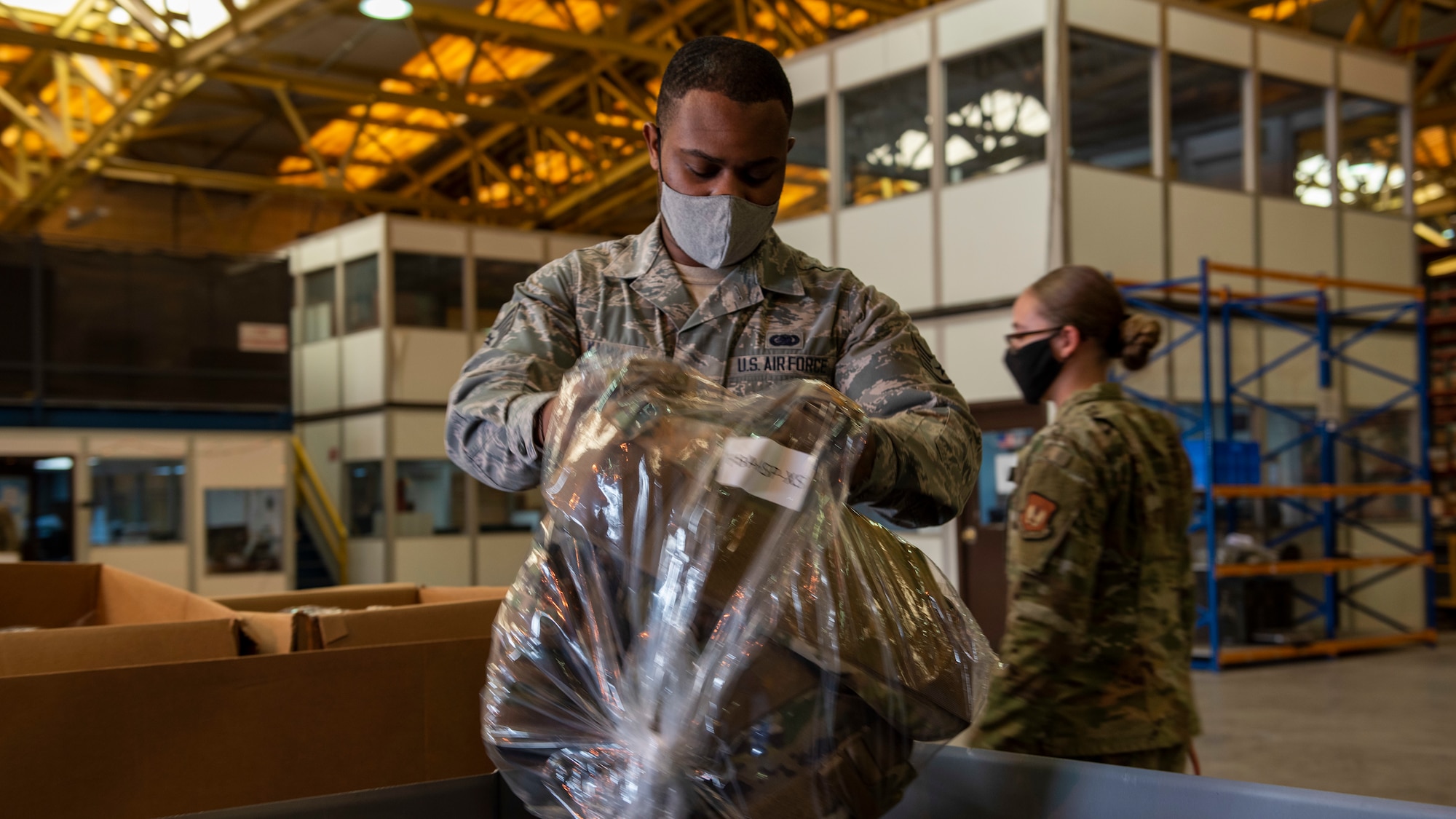 A logistics Airman sorts body armor vests into boxes.