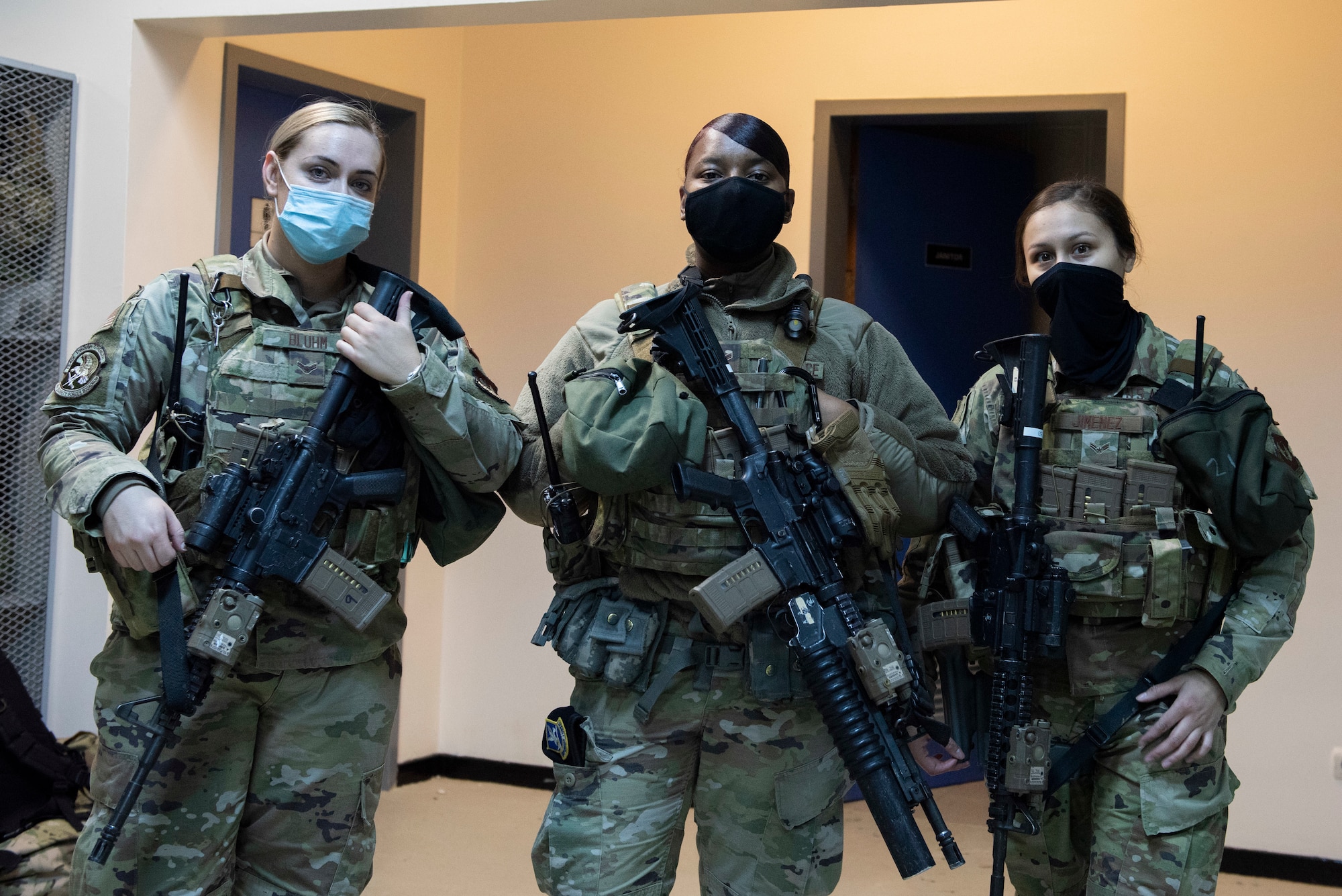 Three women security forces Airmen in full armor and gear pose for a photo.