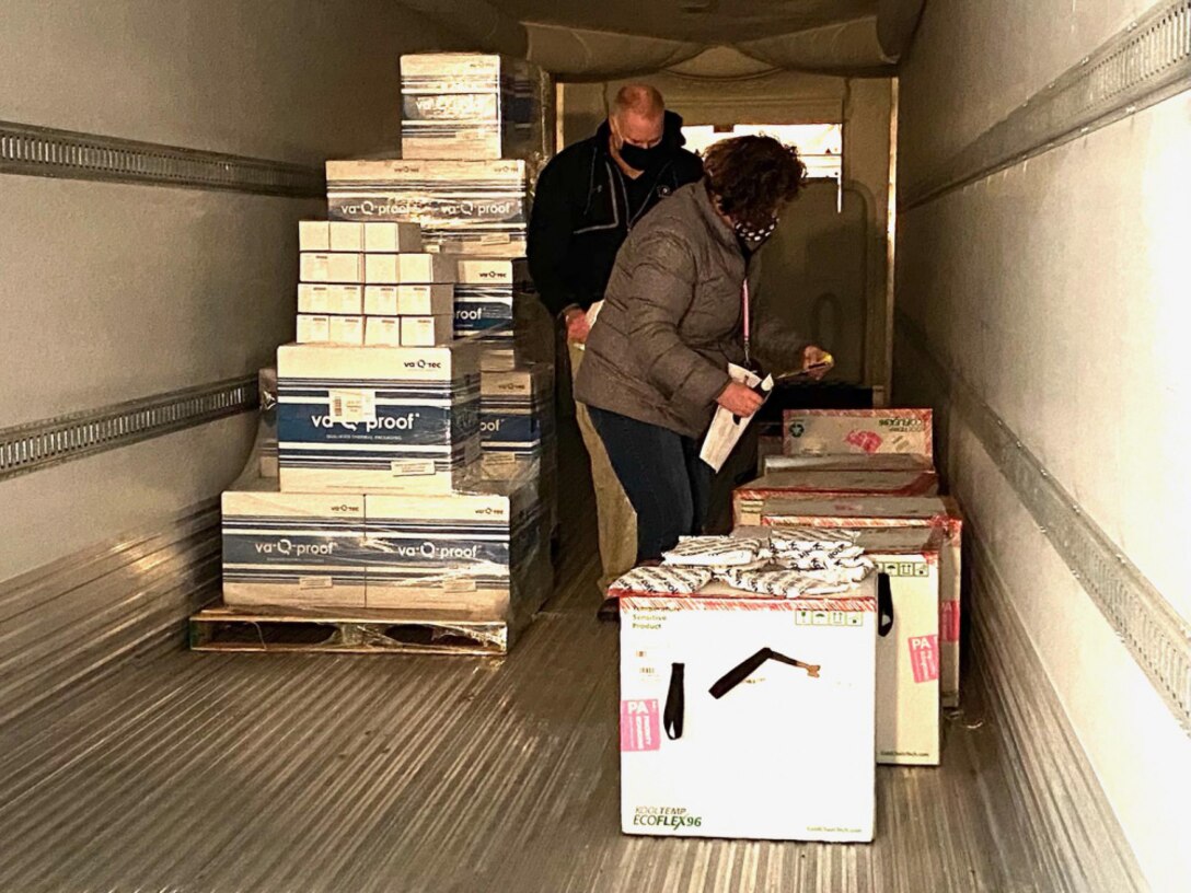 Defense Logistics Agency Distribution Susquehanna employees-Jenny Potts and George Hillman inspect Moderna COVID-19 packages inside the cold storage unit as the vaccines are prepared for shipment to overseas troops and the Navy Fleet.