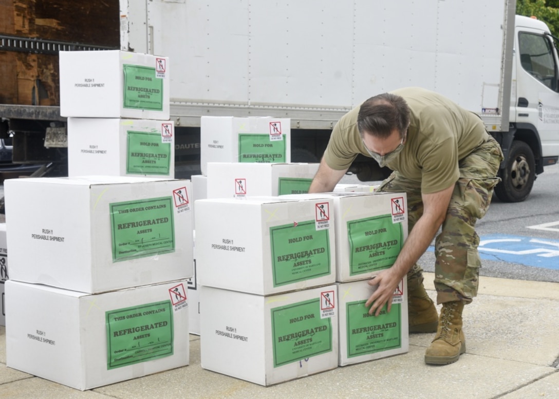 U.S. Air Force Staff Sgt. James Joyner, an aerospace engine mechanic assigned to the 175th Maintenance Squadron, Maryland Air National Guard, stacks boxes of Ramdesiver, a trial COVID-19 medication.