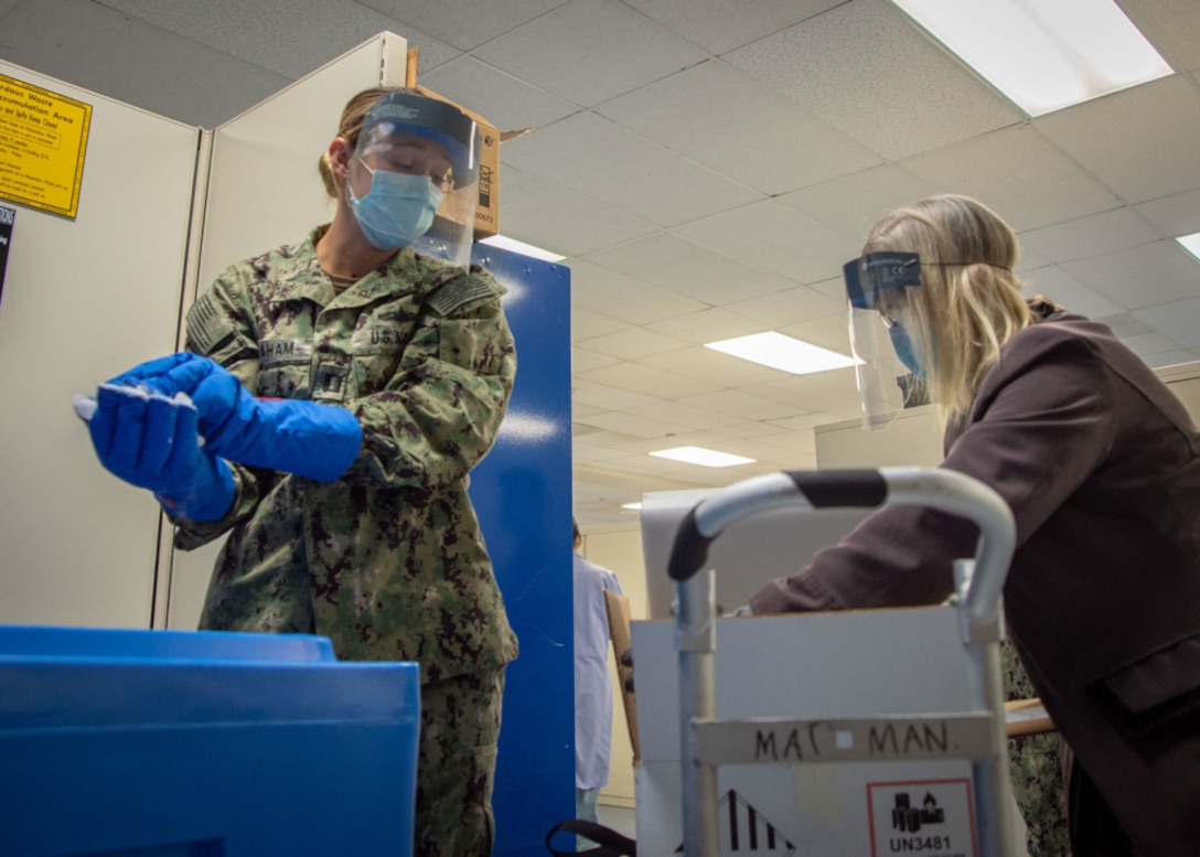 Lt. Devon Graham, Naval Medical Center San Diego’s (NMCSD) material management division officer (left), and Tracey Lopez, NMCSD’s immunizations program director (right), pack a box with dry ice in the hospital’s laboratory.