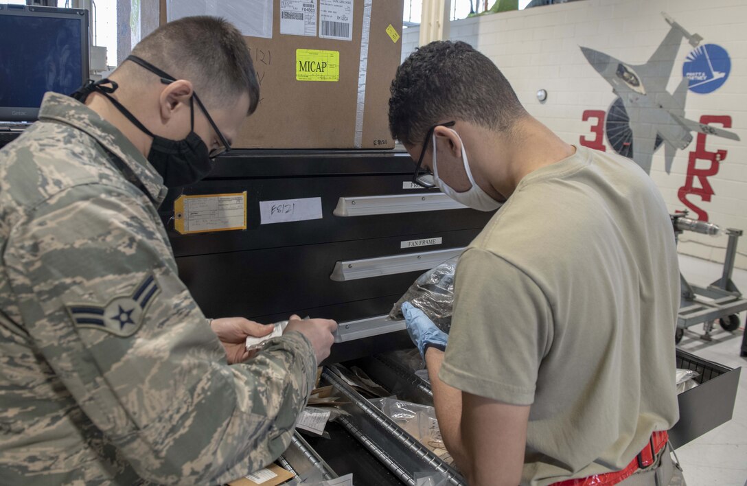 A photo of Airmen looking at parts in a shop.